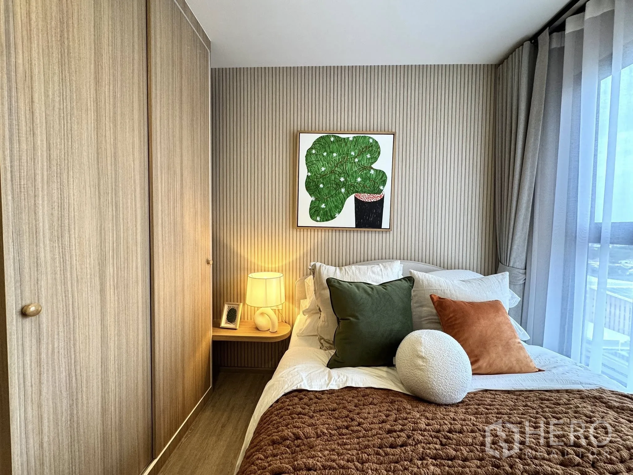 公寓 for rent in Watthana, Bangkok - 卧室配木质衣柜、床头灯、墙面装饰画与纱帘窗户。