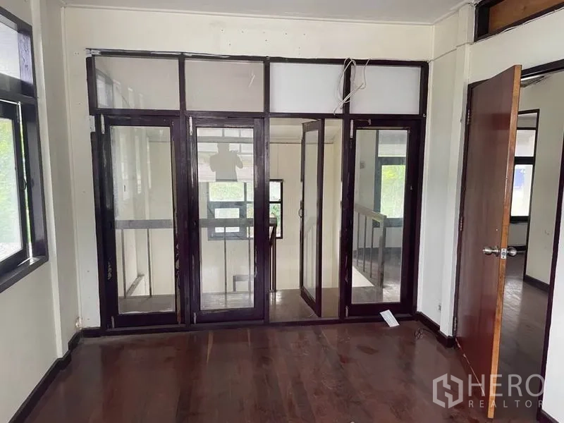 Detached House for rent in Suan Luang, Bangkok - Interior room with multiple framed glass doors beside the staircase landing.