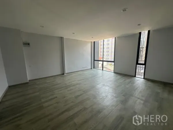 Home Office for rent - Spacious open room with wood-look flooring and corner windows bringing natural light.