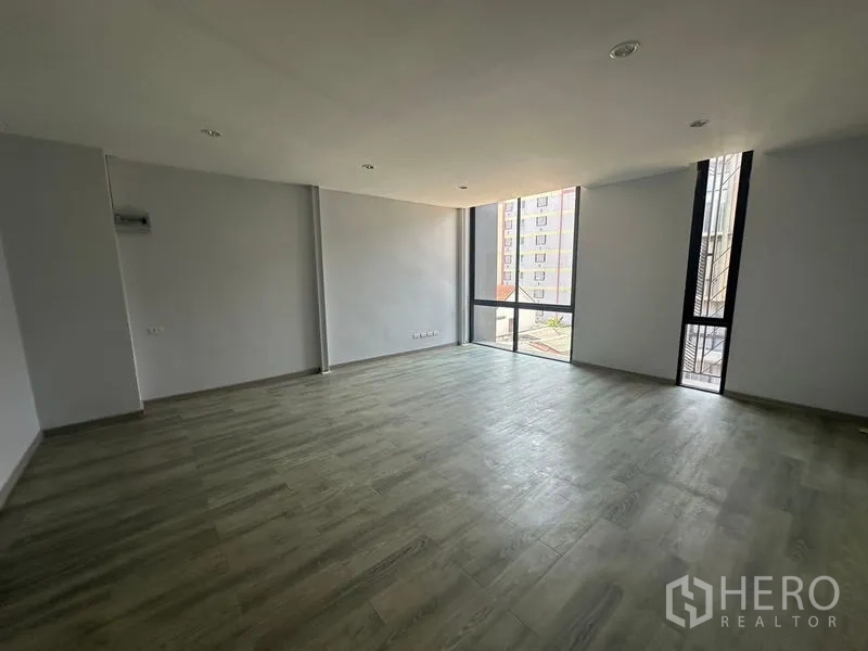 Home Office for rent - Spacious open room with wood-look flooring and corner windows bringing natural light.