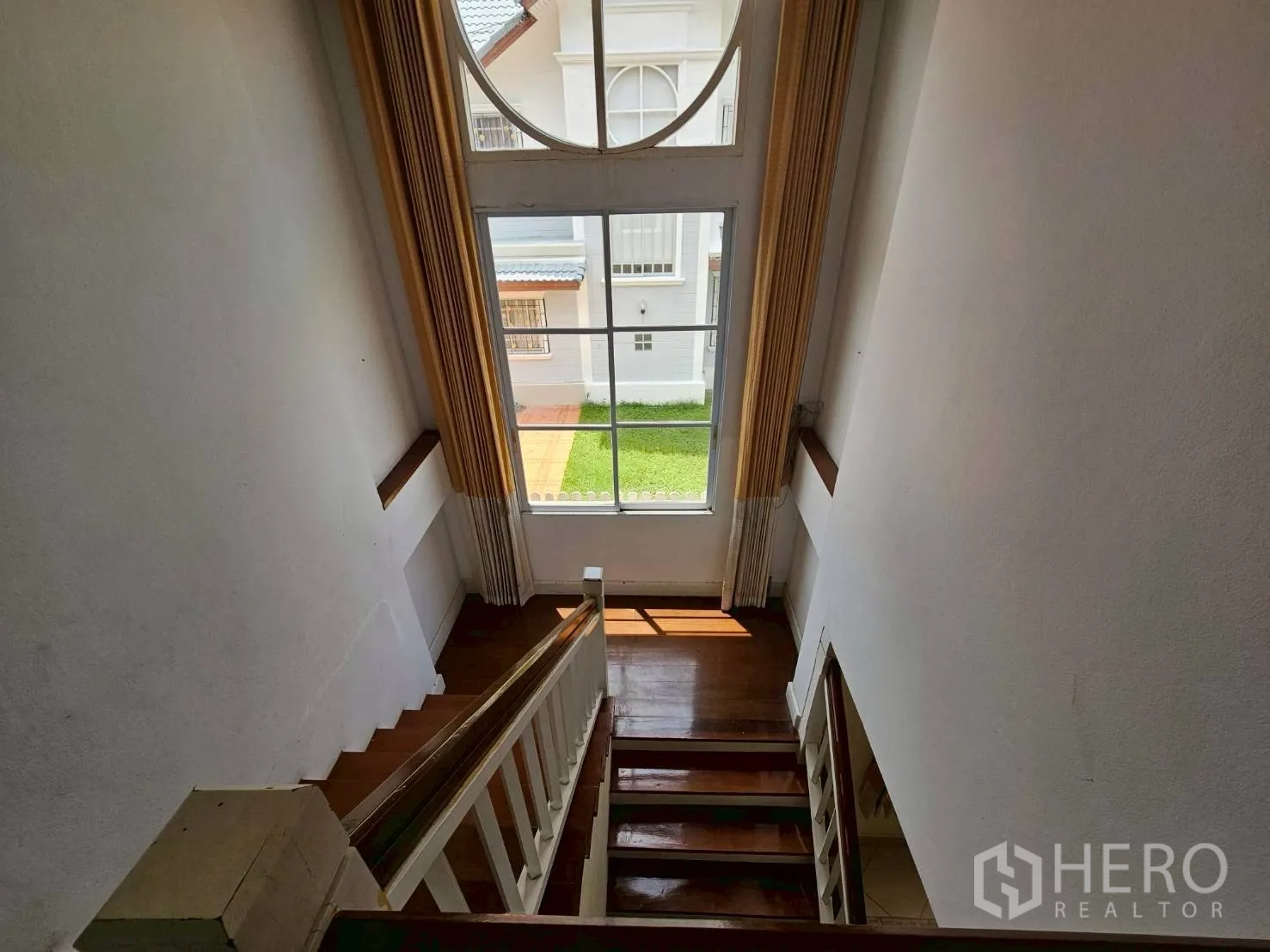 Detached House for rent or sale in Bang Lamung, Chon Buri - Stairwell with tall arched window overlooking the neighborhood.