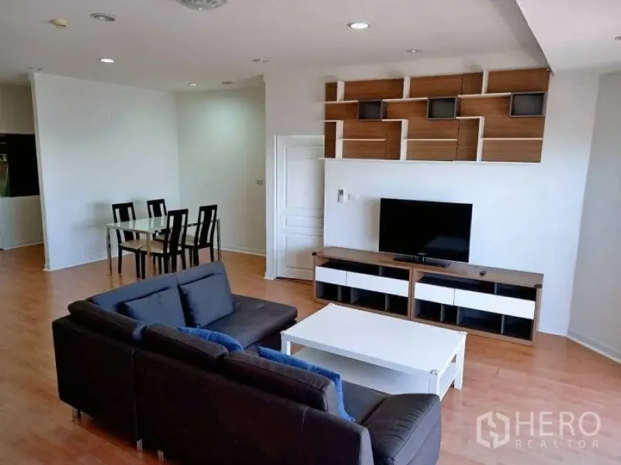 คอนโด ให้เช่าในKhlong Toei, Bangkok - ห้องนั่งเล่นแบบโอเพนพร้อมโซฟาสีเข้ม ทีวี และชั้นลอยลายกราฟิก พื้นไม้