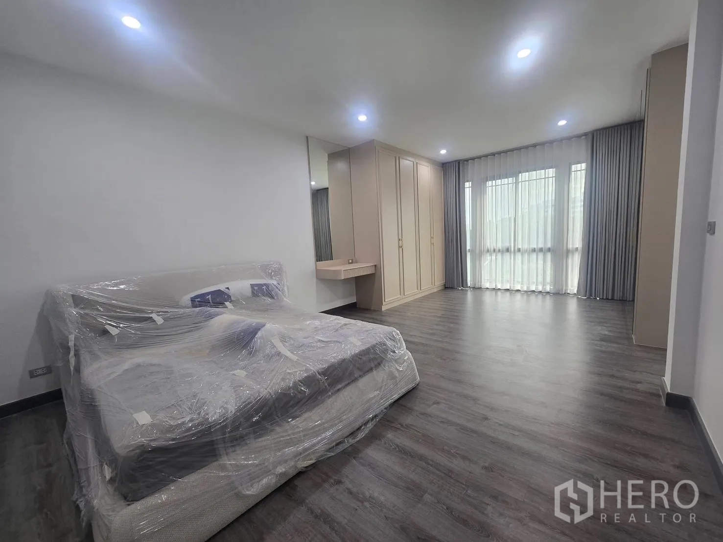 Semi-detached House for rent in Suan Luang, Bangkok - Large bedroom with fitted wardrobe, vanity and wide windows with curtains.