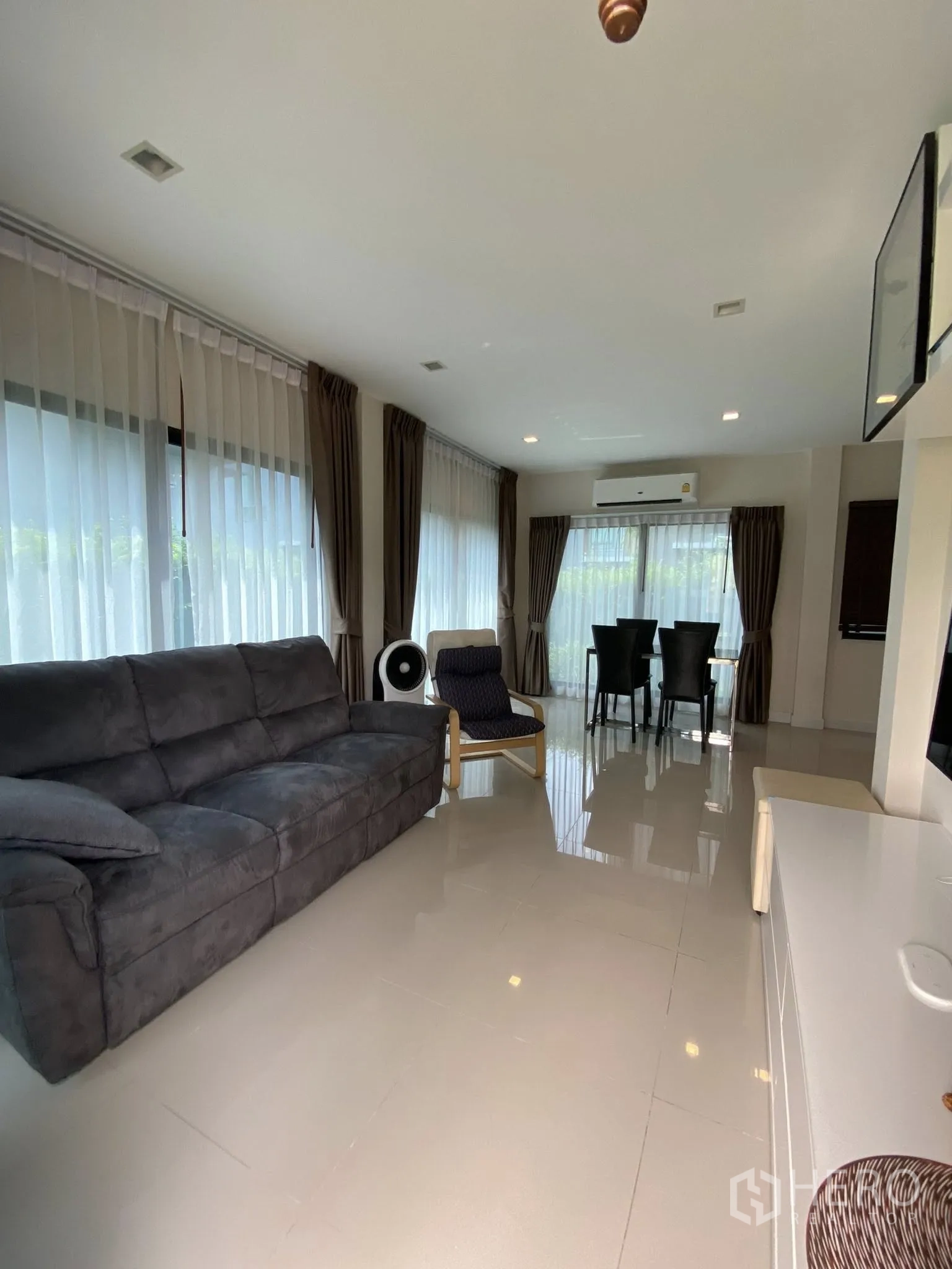 Detached House for sale in Saphan Sung, Bangkok - Open-plan living and dining area with sofa, dining set, and glossy tile floor.