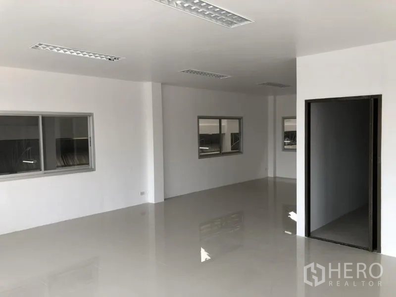 Factory for rent in Pathum Thani - Open-plan office space with multiple windows and LED ceiling lights.