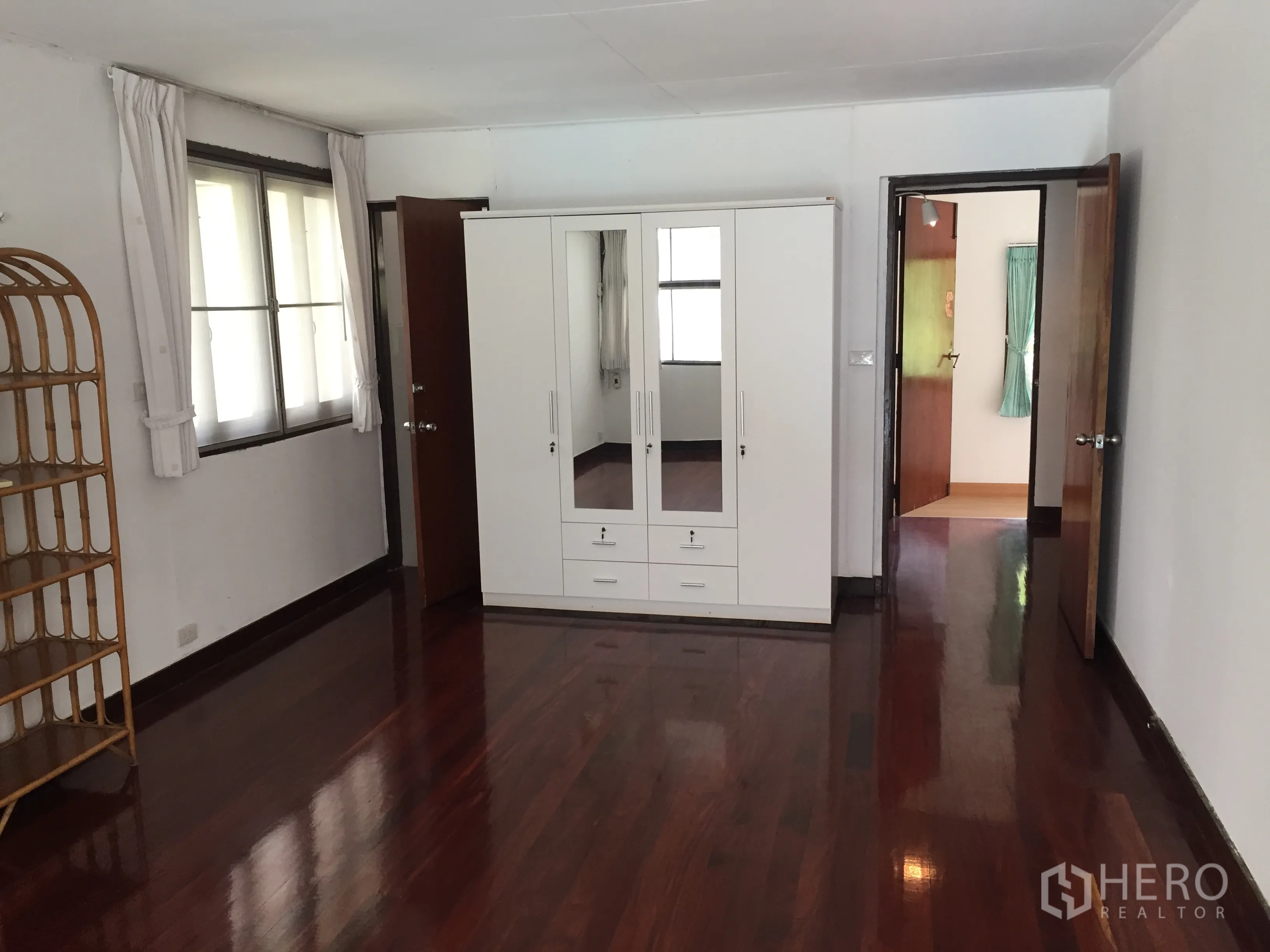 Townhouse for rent in Yan Nawa, Bangkok - Spacious bedroom with glossy wooden flooring and white wardrobe.