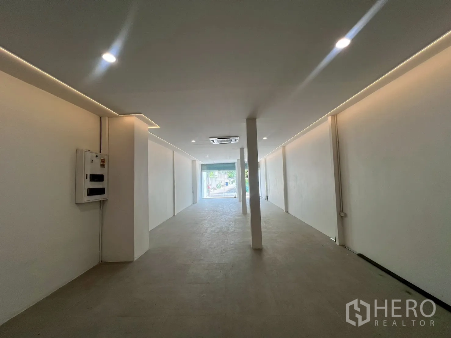 Home Office for rent in Watthana, Bangkok - View from the rear toward the glass front showing a long illuminated open space and electrical panel.