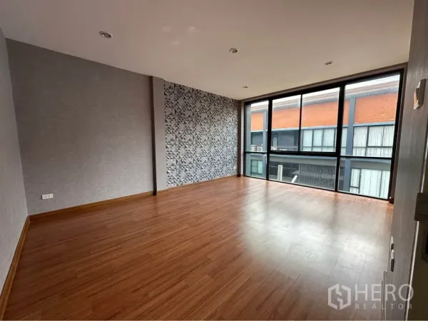 Townhouse for rent in Pak Kret, Nonthaburi - Secondary bedroom with geometric feature wall and expansive glazing.