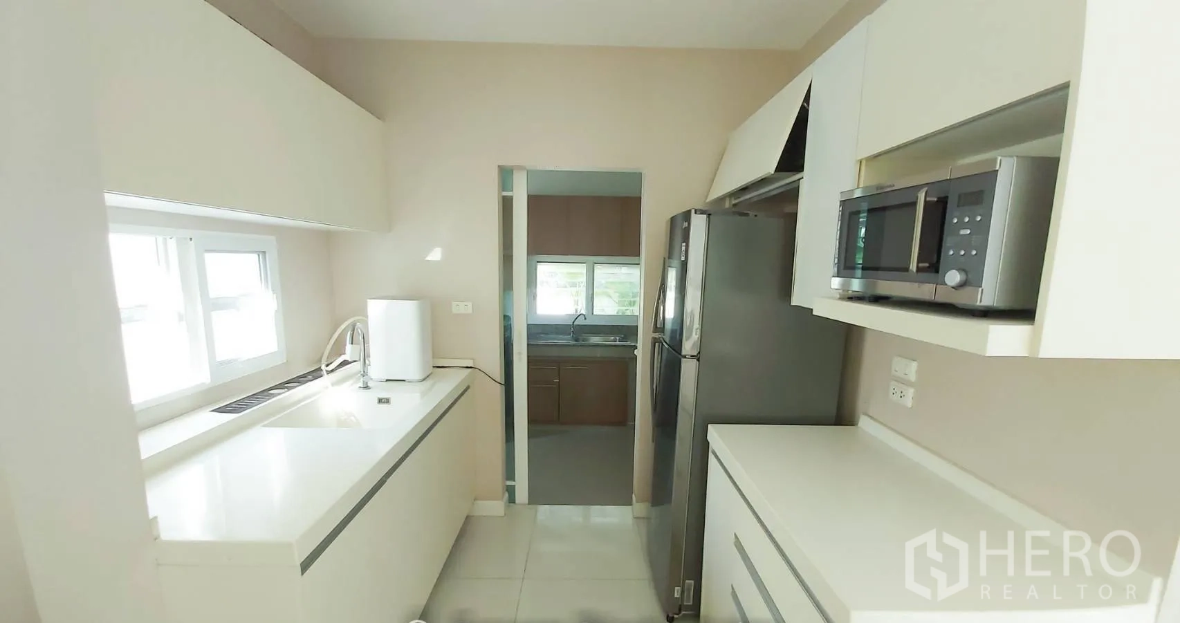 บ้าน for sale in Bang Kapi, Bangkok - ครัวสว่าง เคาน์เตอร์หินสีขาว ตู้บิลท์อิน มีหน้าต่าง เชื่อมไปยังครัวไทย