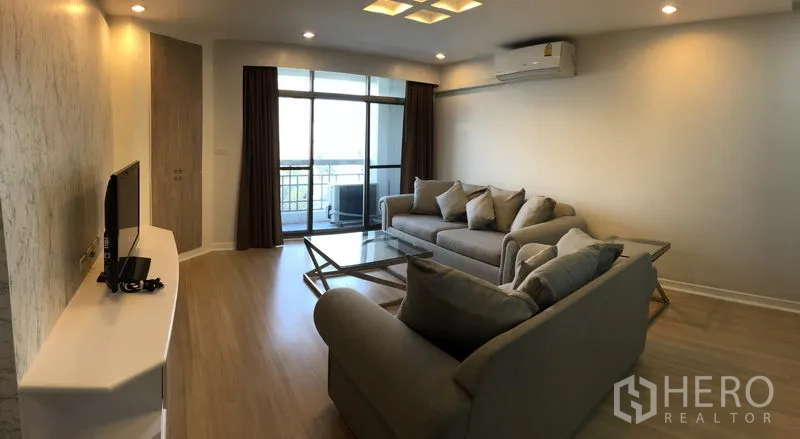 公寓 出租在Watthana, Bangkok - 客厅设沙发组、电视柜、吸顶灯，推拉门通向阳台。