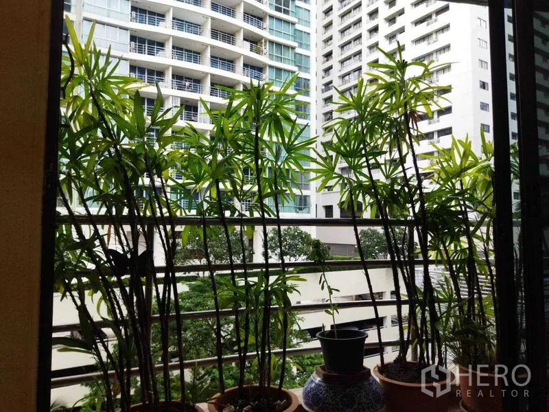 คอนโด ให้เช่าในPathum Wan, Bangkok - มุมมองตึกสูงผ่านต้นไม้ที่ระเบียง เห็นอาคารสมัยใหม่และพื้นที่สีเขียว