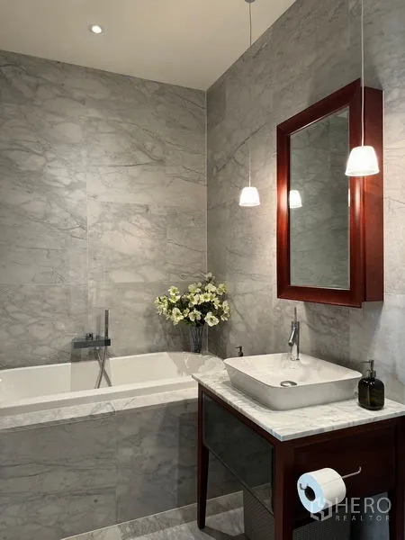 Condominium for sale in Watthana, Bangkok - Marble bathroom showcasing a soaking tub, vanity and warm pendant lighting.