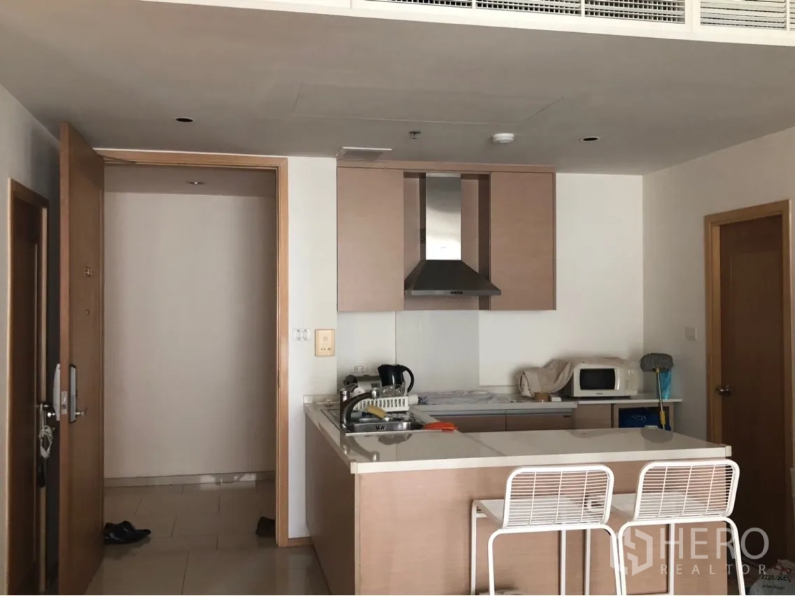 公寓 出租或出售在Sathon, Bangkok - 木质柜体的现代厨房，带中岛吧台、两把高脚椅与抽油烟机。