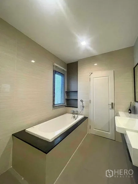 บ้าน ขายในBang Kruai, Nonthaburi - ห้องน้ำสว่างพร้อมอ่างอาบน้ำบิลต์อิน หน้าต่างติดม่าน และเคาน์เตอร์ล้างหน้าโทนสีเอิร์ธ