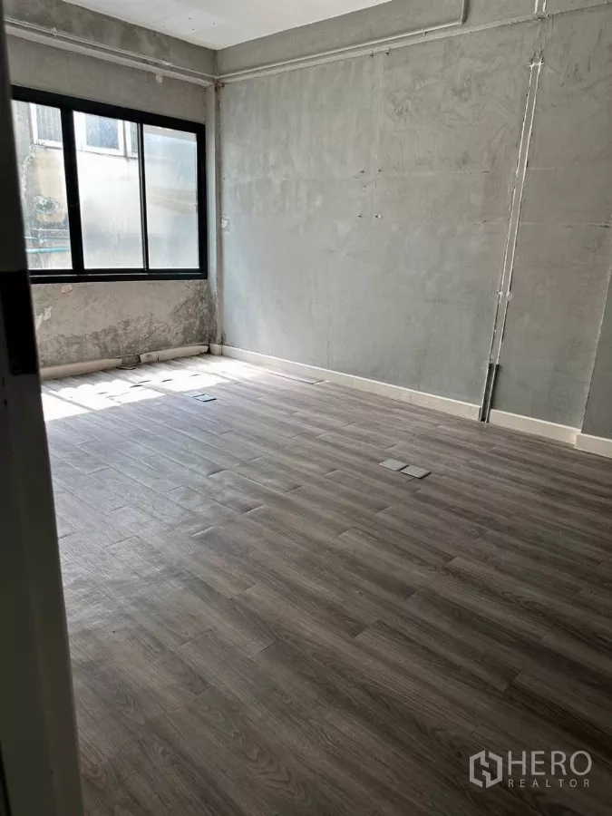 อาคารพาณิชย์ ขายในWatthana, Bangkok - ห้องผนังคอนกรีตสำเร็จรูป มีหน้าต่างบานกว้างและพื้นลายไม้.