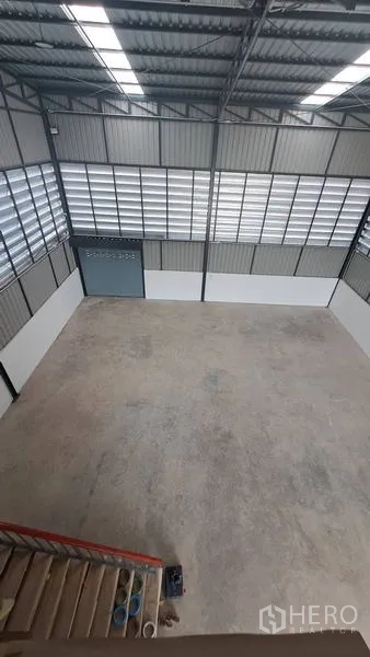 Warehouse for rent in Lam Luk Ka, Pathum Thani - Bird’s-eye view of spacious warehouse floor with louvered wall panels and skylights.