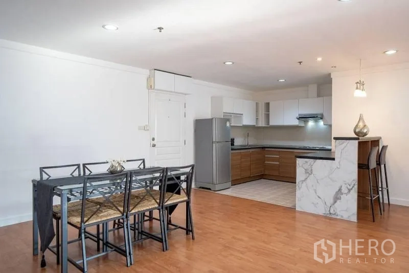 公寓 出租在Khlong Toei, Bangkok - 开放式餐厨区，带大理石吧台、餐桌组与不锈钢冰箱。