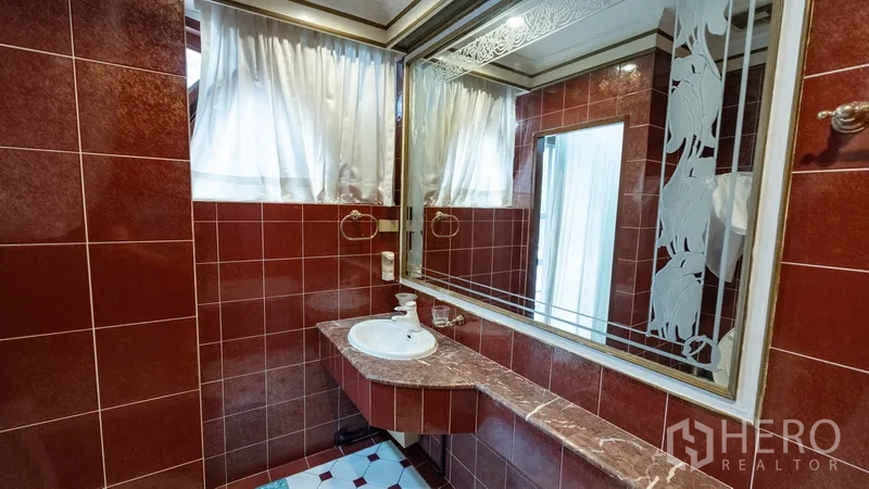 Townhouse for rent in Khlong Toei, Bangkok - Red‑tiled bathroom vanity with large etched mirror and countertop basin.
