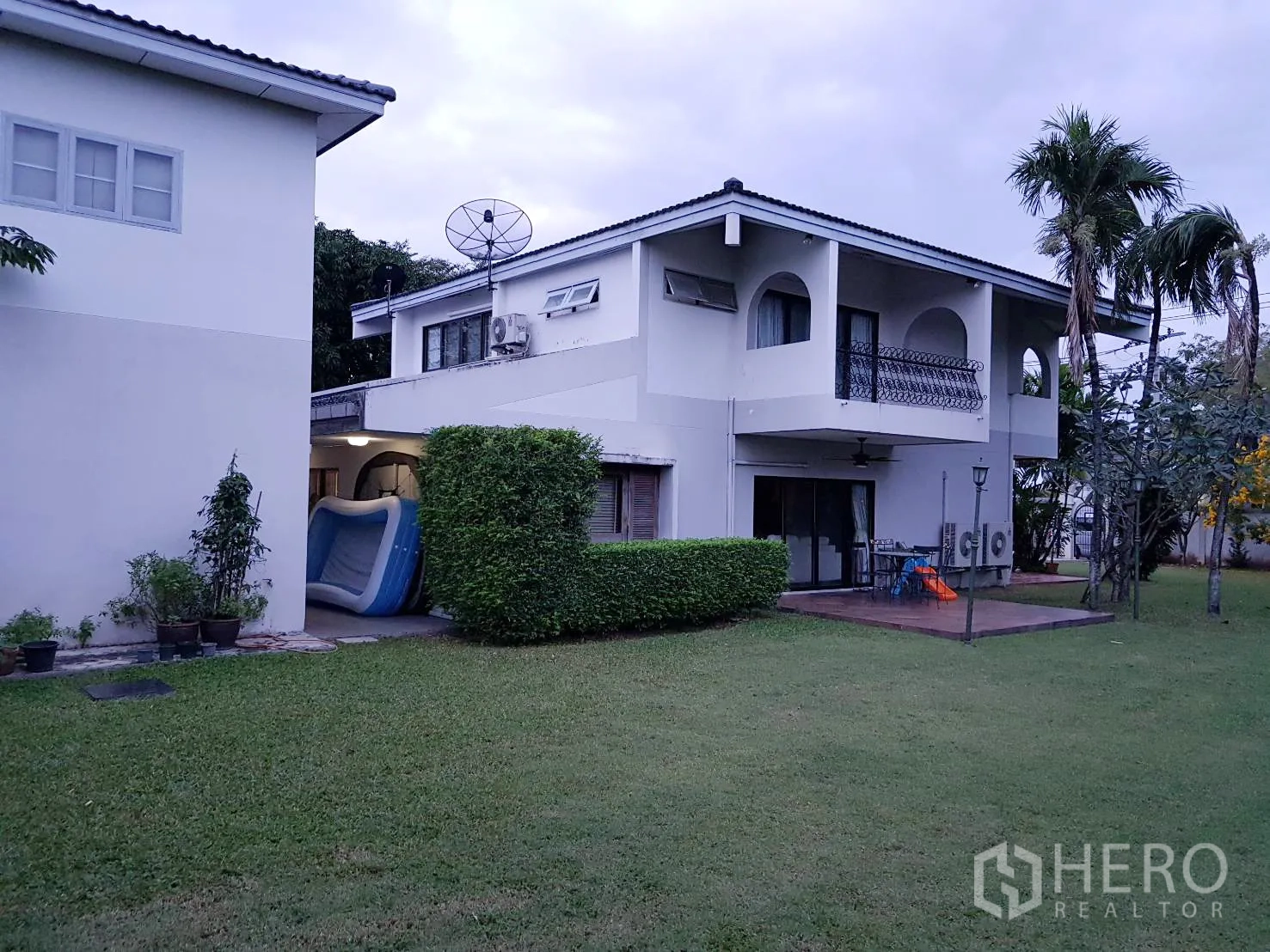 บ้าน ให้เช่าในKhan Na Yao, Bangkok - ด้านหลังบ้านสองชั้นสีขาว มีระเบียง ชานไม้ และสนามหญ้ากว้าง