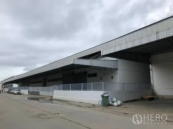 Warehouse for rent in Bang Bo, Samut Prakan - Long warehouse exterior with wide covered loading dock, metal roof canopy and fenced platform.