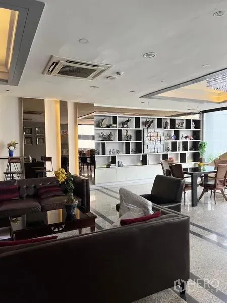 Condominium for rent in Ratchathewi, Bangkok - Modern condo lounge with sofas, built-in shelving and large windows.