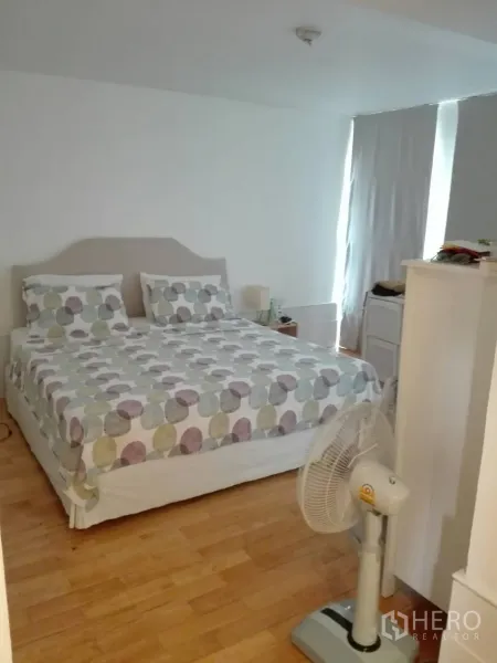 คอนโด ให้เช่าในKhlong Toei, Bangkok - ห้องนอนขนาดกว้าง เตียงคู่ พื้นไม้ และผ้าม่านทึบแสง พร้อมพัดลมตั้งพื้น