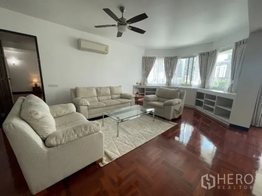 公寓 出租在Khlong Toei, Bangkok - 宽敞客厅，拼花木地板、米色沙发、吊扇与转角飘窗，空堤区公寓城市景观