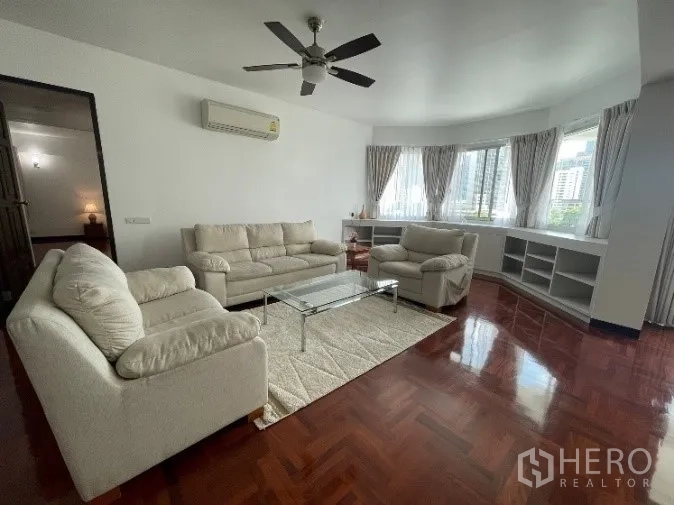 公寓 出租在Khlong Toei, Bangkok - 宽敞客厅，拼花木地板、米色沙发、吊扇与转角飘窗，空堤区公寓城市景观