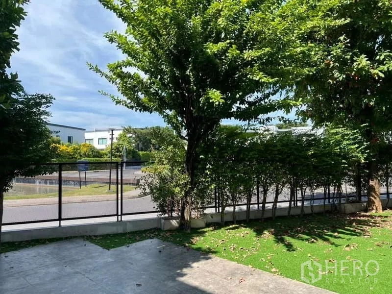 Detached House for rent or sale in Bang Phli, Samut Prakan - Front garden with shade trees, trimmed hedge and view toward the roadway.