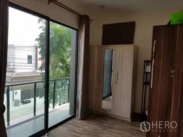 Detached House for sale in Samut Prakan - Room with sliding glass doors to a balcony, wardrobe and a view of the neighborhood.
