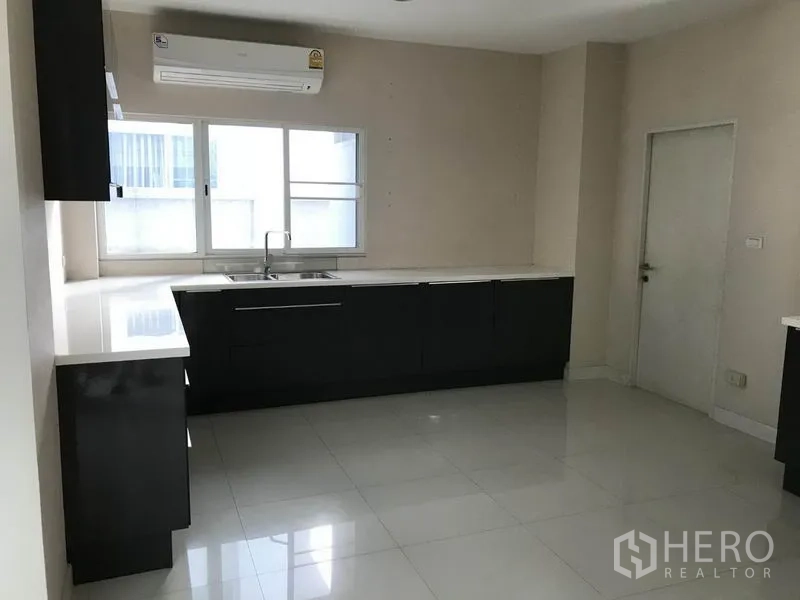 Detached House for sale in Suan Luang, Bangkok - Bright kitchen with black cabinetry, white countertops, window and tiled floor.