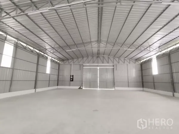Warehouse for rent in Sai Mai, Bangkok - Open warehouse floor facing large double metal doors with bright natural light.