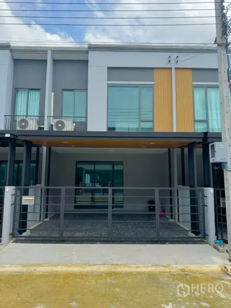 Townhouse for rent in Bang Phli, Samut Prakan - Modern two-storey townhome exterior with gated, covered parking for two cars.