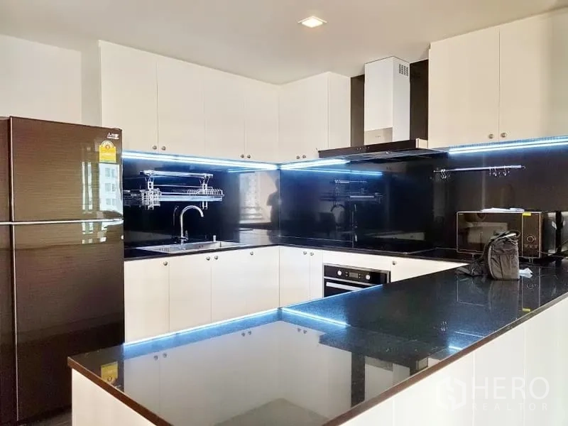公寓 出租在Watthana, Bangkok - 现代U形厨房，黑色花岗岩台面、白色橱柜与LED灯带。