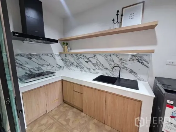 ทาวน์เฮาส์ ให้เช่าในSuan Luang, Bangkok - ครัวขนาดกะทัดรัด แผงกันเปื้อนลายหินอ่อน อ่างล้างจานสีดำ เตา พร้อมเครื่องดูดควัน และตู้ไม้บิวต์อิน