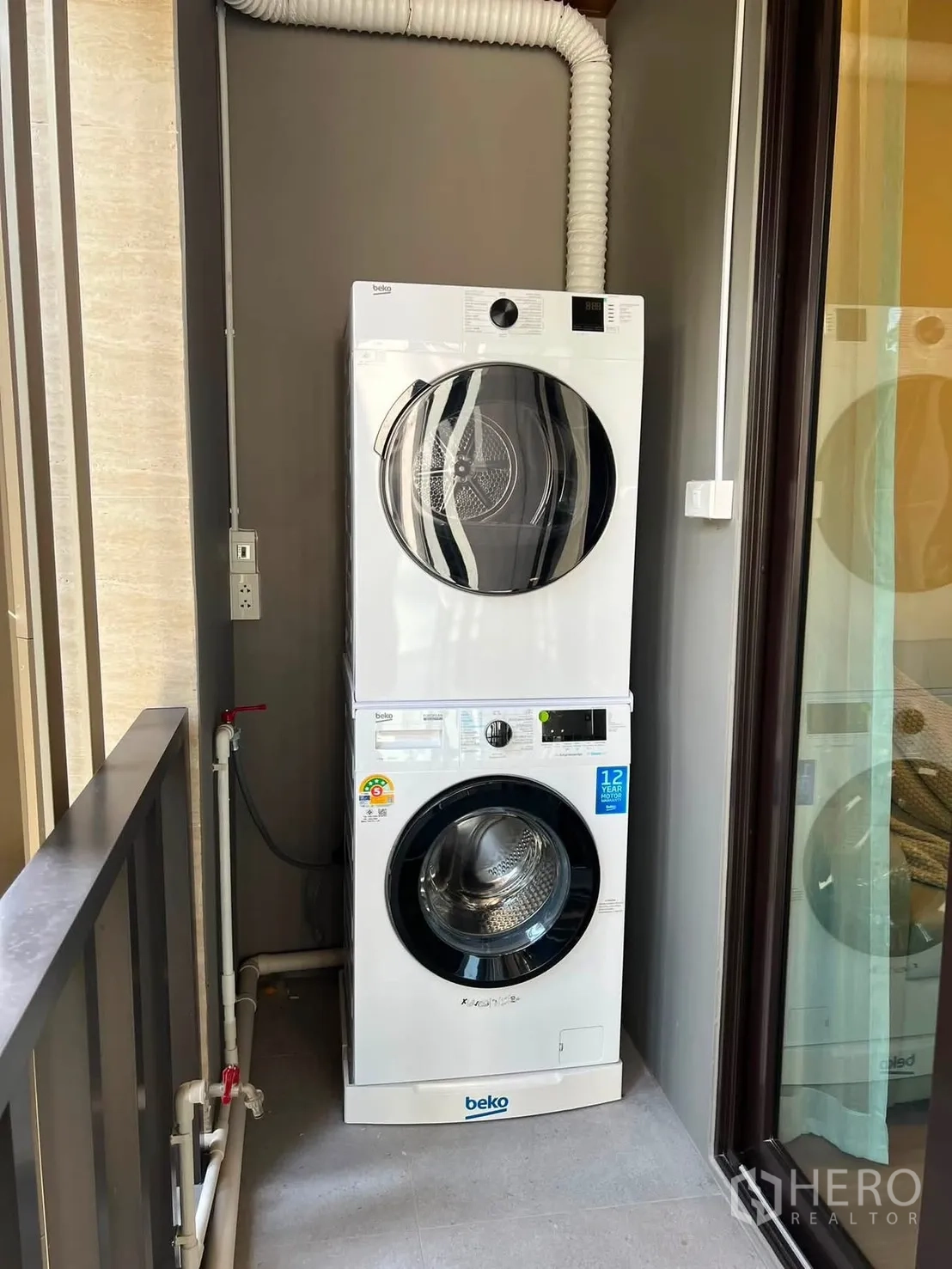 Detached House for rent in Bang Phli, Samut Prakan - Laundry nook with stacked washer and dryer next to a glass door.