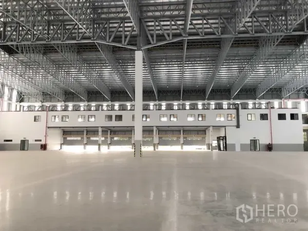 工厂 出租或出售在Samut Prakan - 仓库中央视角，多个卷帘门与立柱，宽跨屋架上方清晰可见。