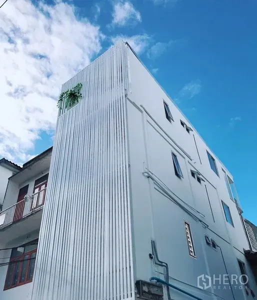 Retail Space for rent in Khlong Toei, Bangkok - Modern white shophouse exterior with corrugated metal facade under a blue sky in Phra Khanong, Bangkok.
