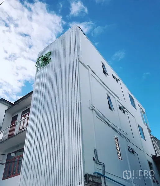 Retail Space for rent in Khlong Toei, Bangkok - Modern white shophouse exterior with corrugated metal facade under a blue sky in Phra Khanong, Bangkok.