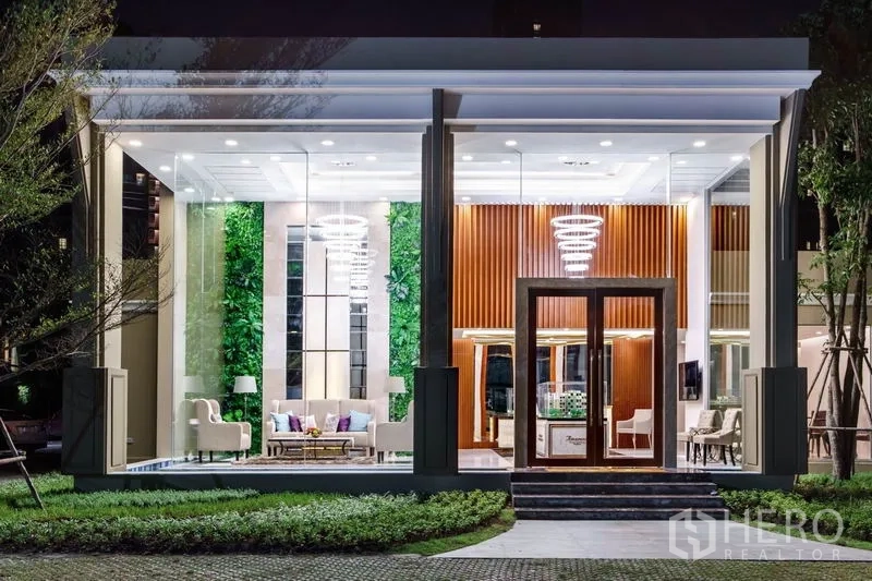 Condominium for sale in Huai Khwang, Bangkok - Elegant double-height lobby pavilion with glass walls, lounge seating and feature lighting at night.