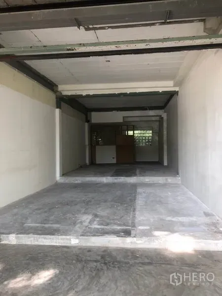 零售空间 出租在Watthana, Bangkok - 进深店铺，局部抬高地面、白色墙面与后方工作区。