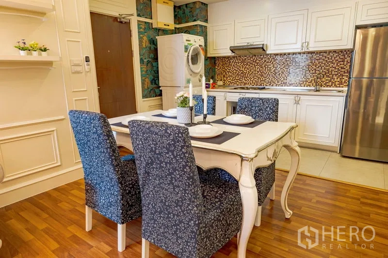 Condominium for rent in Watthana, Bangkok - White kitchen with mosaic backsplash beside dining table, plus stacked washer–dryer and stainless refrigerator.