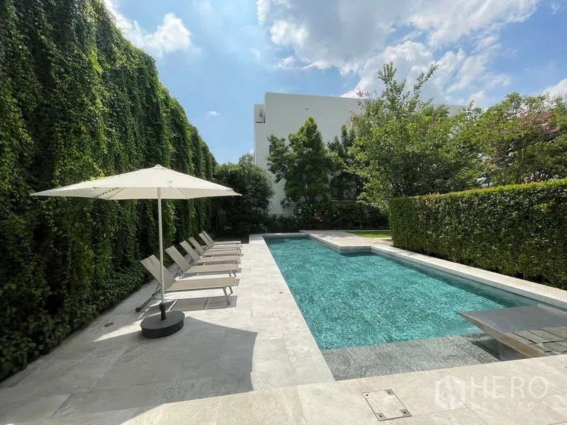 สำนักงานที่บ้าน ให้เช่าในDon Mueang, Bangkok - สระว่ายน้ำยาวกลางแจ้ง พร้อมเตียงอาบแดด ร่ม และกำแพงต้นไม้สูง