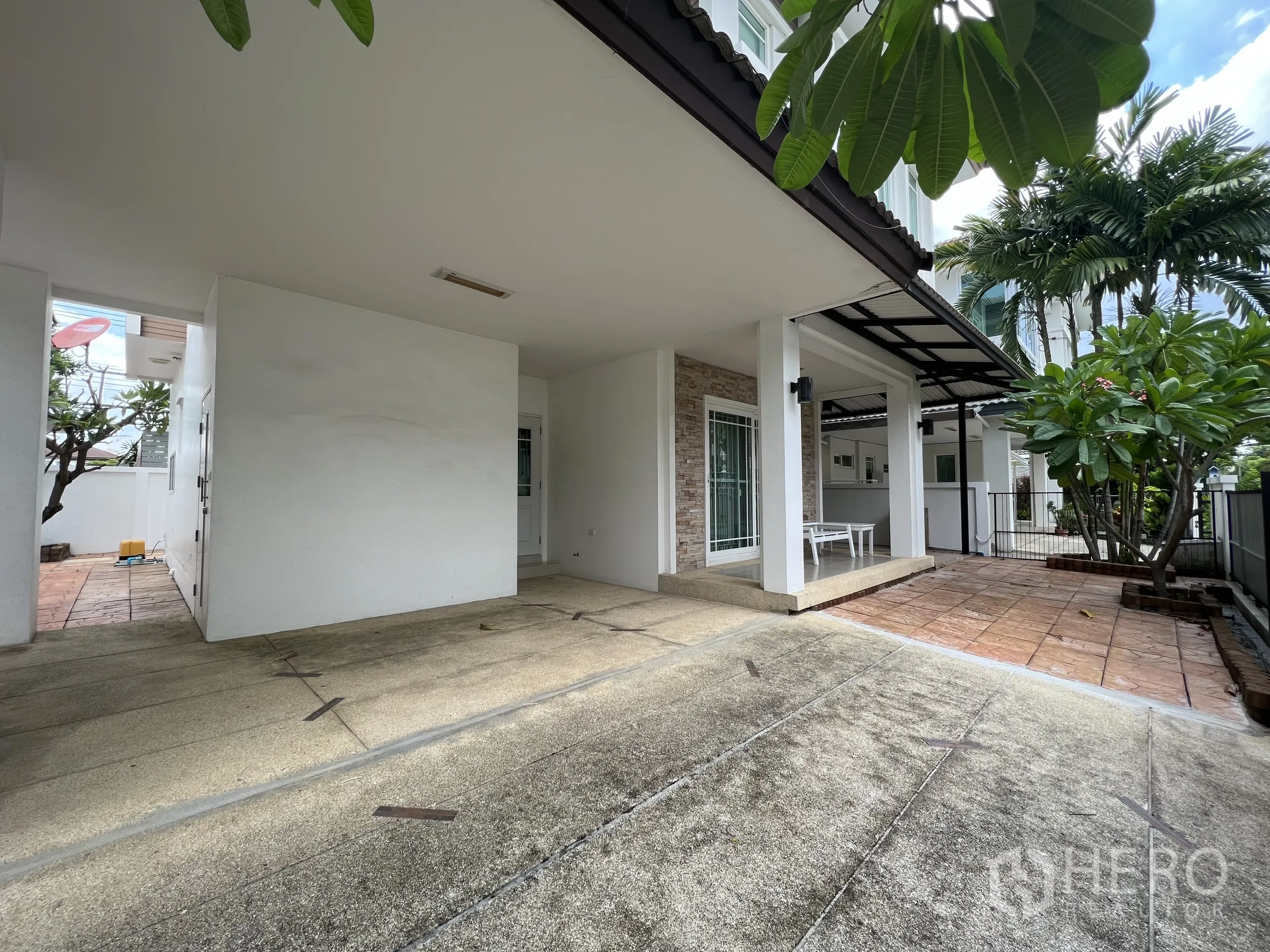 Detached House for rent in Bang Kapi, Bangkok - Covered carport and tiled front porch beside a small garden at the two-storey home.