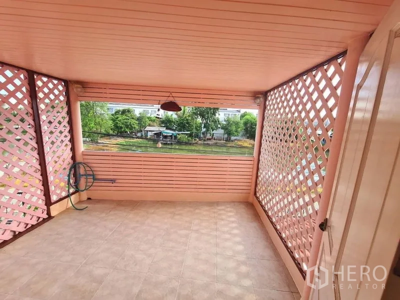 บ้าน ให้เช่าในSai Mai, Bangkok - ระเบียงกึ่งเอาต์ดอร์กรุระแนงสีชมพู มองเห็นวิวบ่อน้ำที่เงียบสงบ