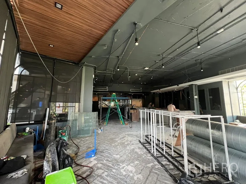 พื้นที่ขายปลีก ให้เช่า - โถงค้าขายโล่ง เพดานไม้ โคมไฟแขวน และท่อแอร์รอการติดตั้ง