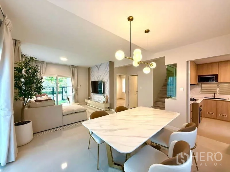 Detached House for rent in Bang Phli, Samut Prakan - Dining area with marble table and pendant lights facing living and kitchen.