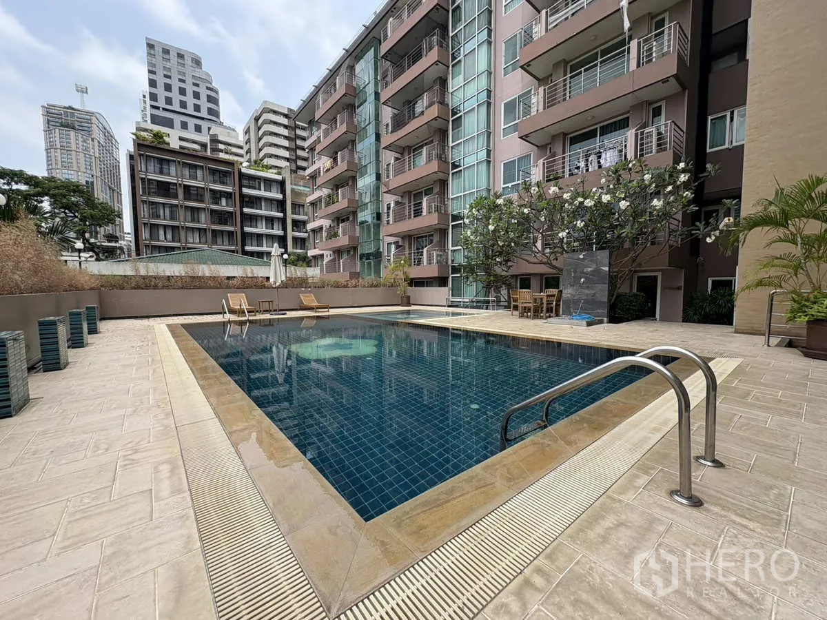 公寓 出租在Khlong Toei, Bangkok - 泳池边视角，入水梯与躺椅，旁为公寓立面。