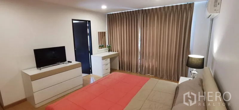 อพาร์ทเมนท์ ให้เช่าในKhlong Toei, Bangkok - ห้องนอนหลักพร้อมโต๊ะเครื่องแป้ง ตู้วางทีวี และหน้าต่างใหญ่พร้อมม่าน