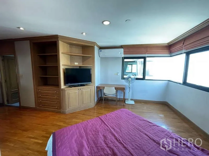 คอนโด ให้เช่า - มุมห้องนอนพร้อมตู้วางทีวี ชั้นวางของ โต๊ะทำงาน และหน้าต่างรอบด้าน